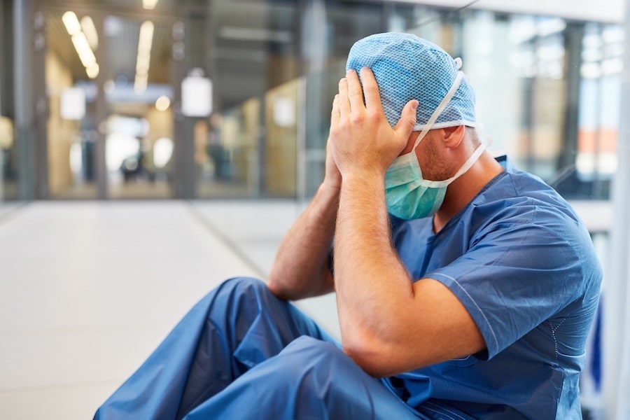 Doctor Sitting On The Floor Holding His Head Photo of Doctor Sitting On The Floor Holding His Head